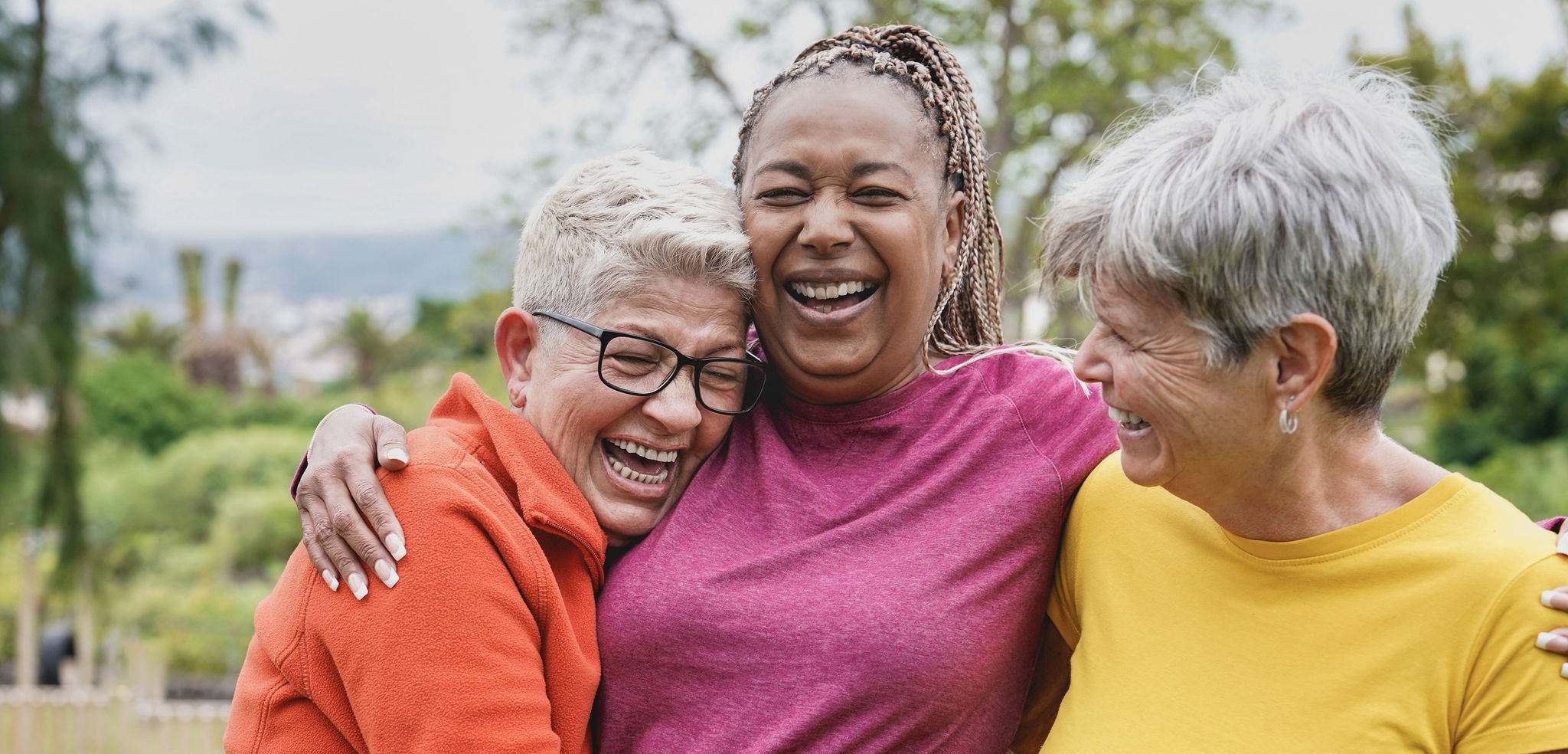 Happy multiracial senior women having fun together at park - Elderly generation people hugging each other outdoorBrandfolder photography
