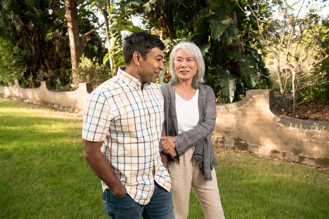 A man and woman linking arms for support walking in garden