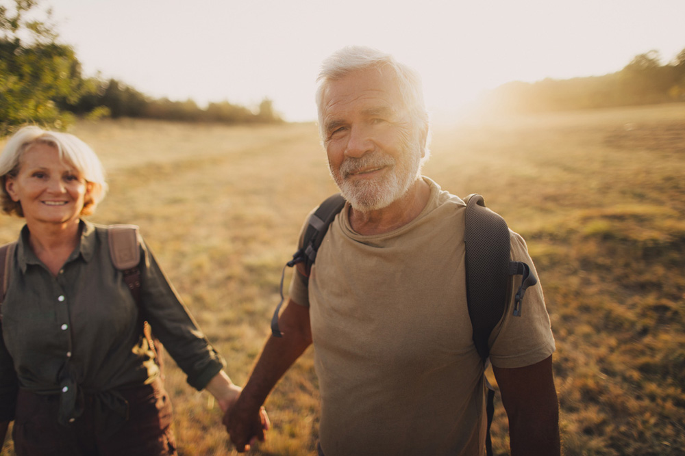 Photo of an elderly couple who still enjoy making memories, searching for new adventures while backpacking