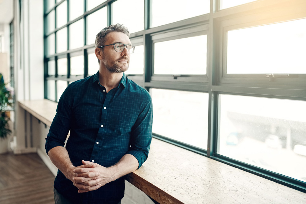 Shot of a mature businessman looking thoughtfully out of an office window