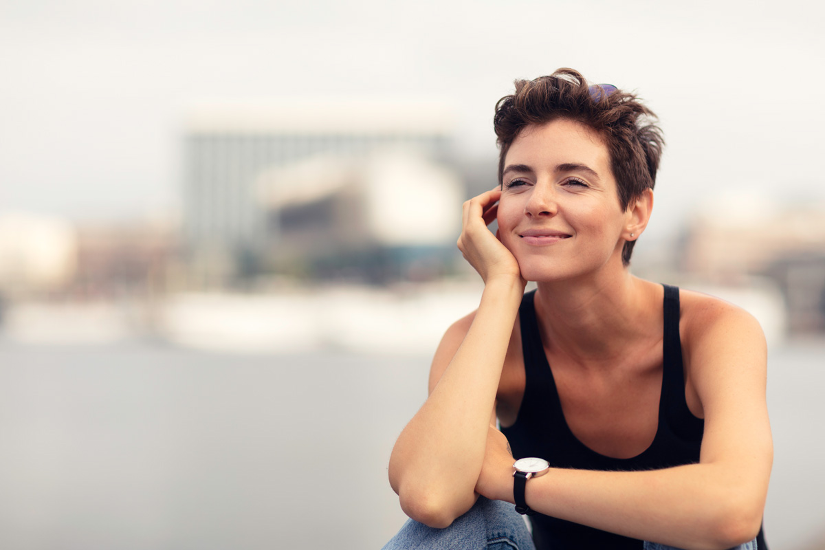 A woman sitting by the quay in central Stockholm and enjoying a summer day.