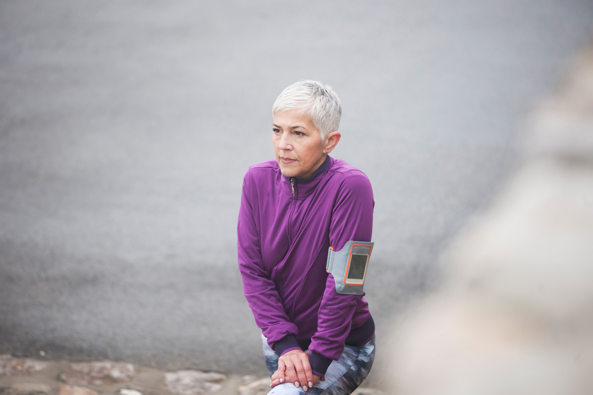 Beautiful mature woman jogging through fog in early autumn day