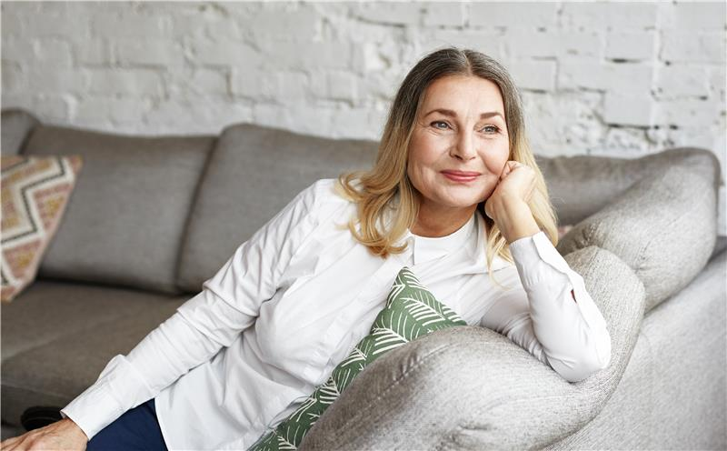 Woman in white top on grey couch