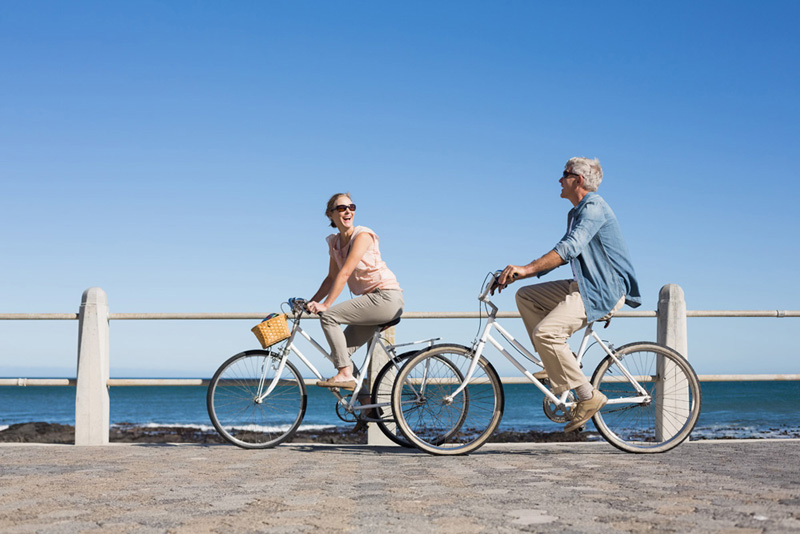 Happy casual couple going for a bike ride on the pier on a sunny day