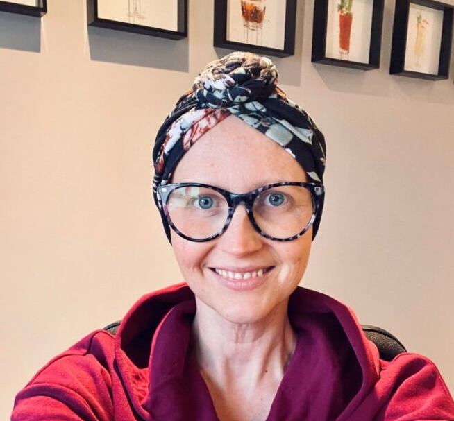 GenesisCare patient Caroline sitting in her kitchen smiling