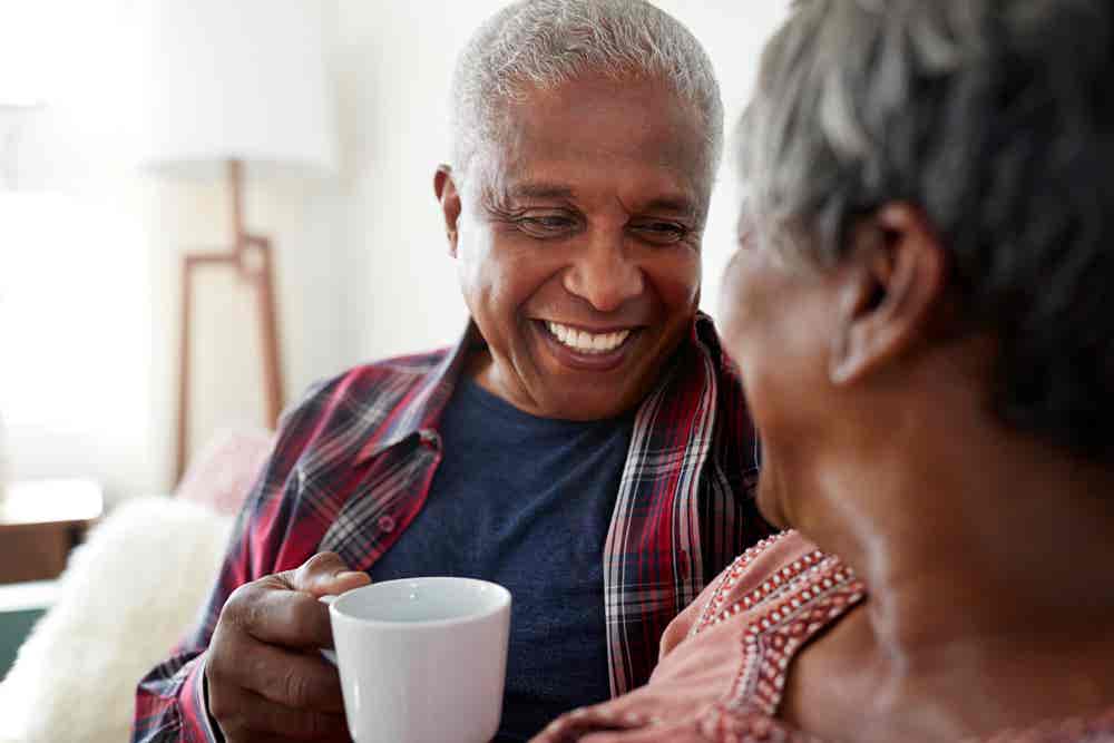 Senior Couple Sitting On Sofa At Home Relaxing With Hot Drink