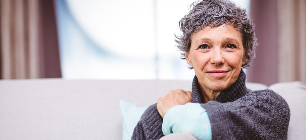 Portrait of smiling mature woman sitting on sofa at home