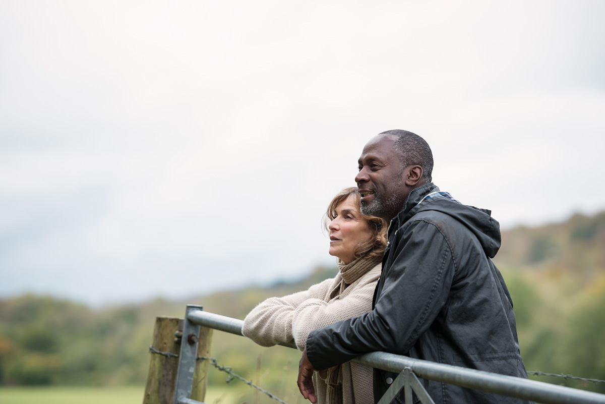 Mature Couple leaning on gate in open countryside.