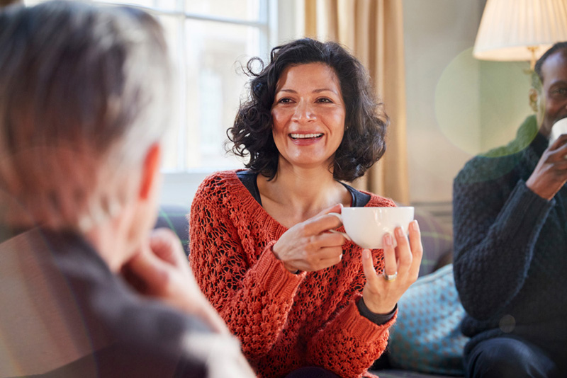 Middle Aged Woman Meeting Friends Around Table In Coffee Shop