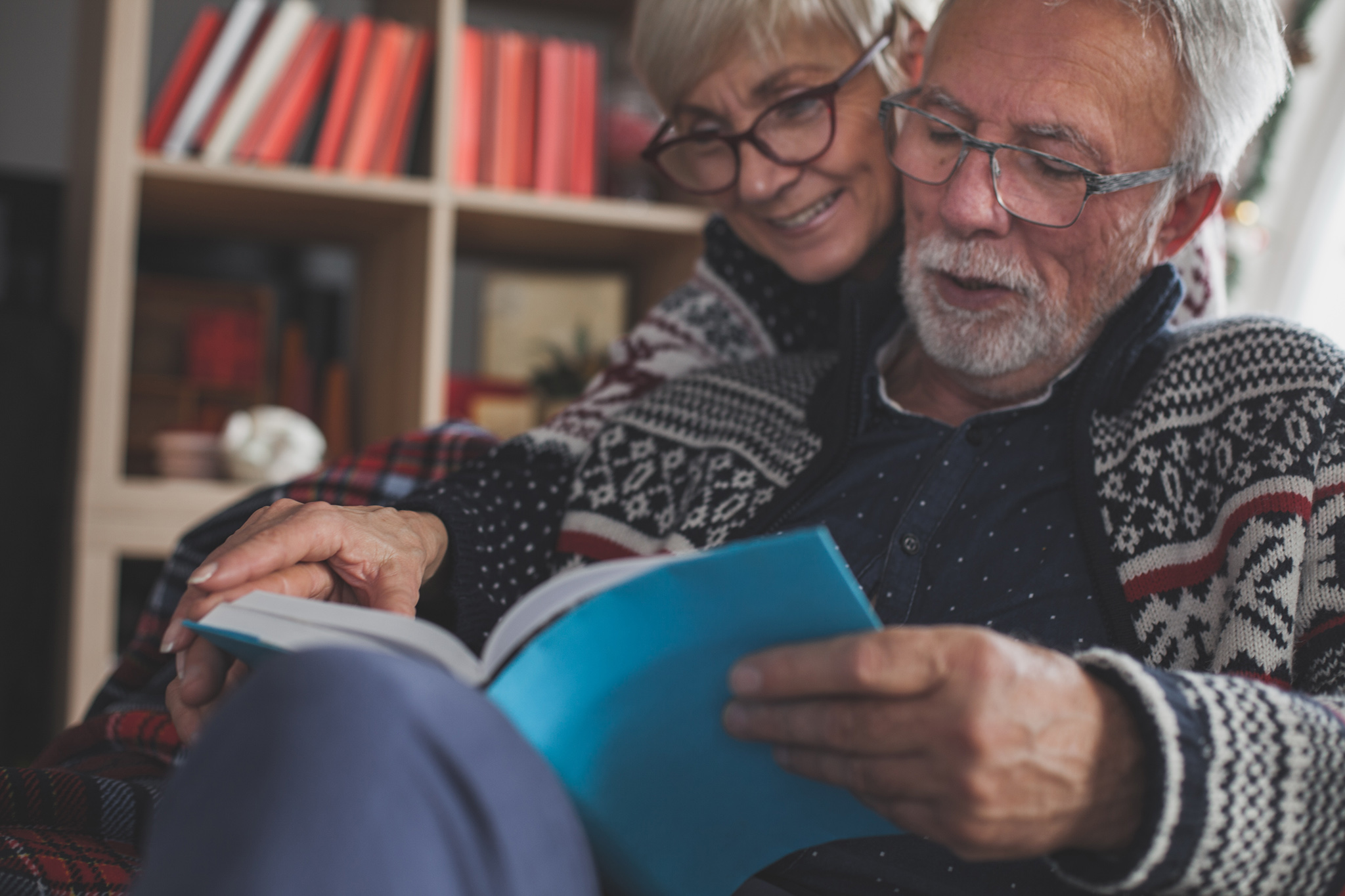 GL_couple-reading_hero-banner Senior married couple in cozy winters clothes relaxing and enjoying reading a book together.