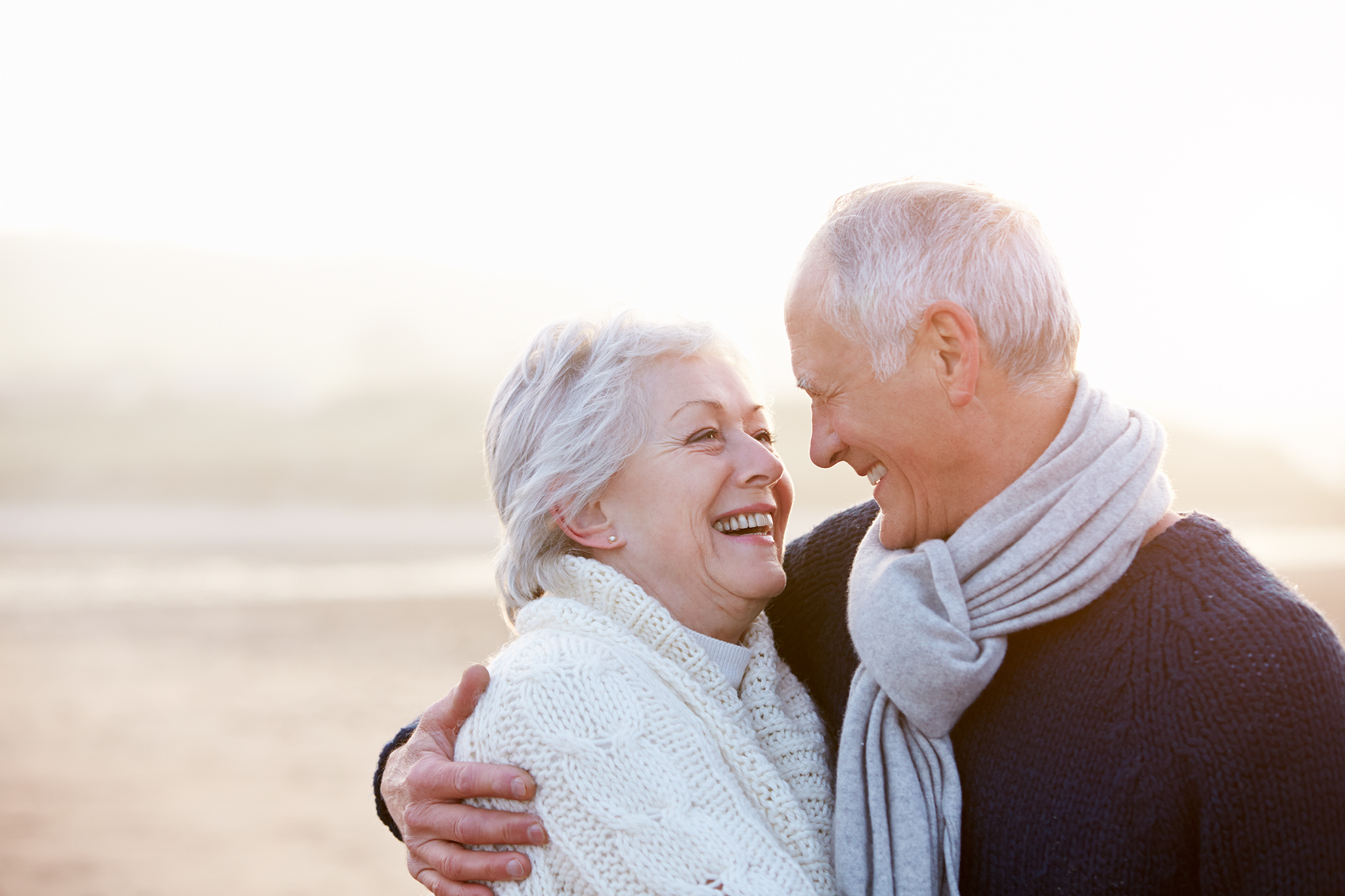Romantic Senior Couple On Winter Beach Smiling At Eachother