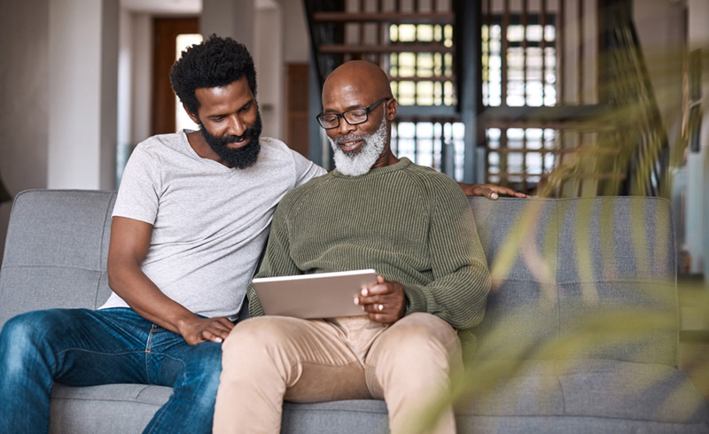 Shot of a happy senior man using a digital tablet while spending some time with his adult son at home