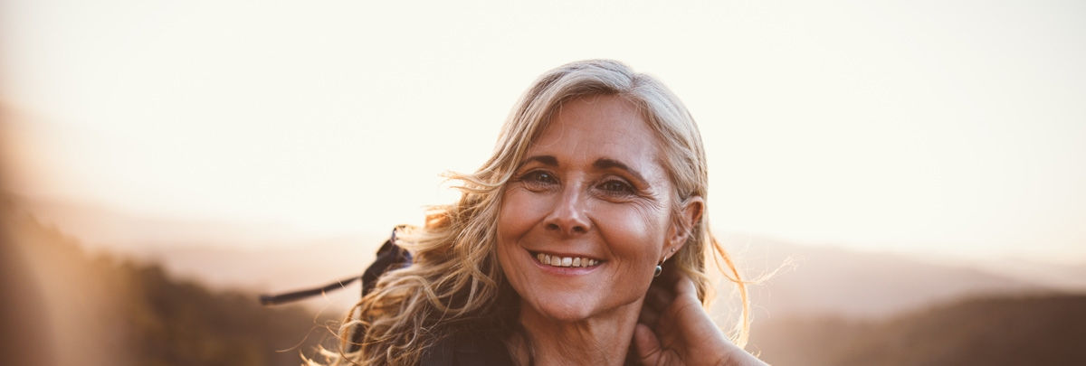 Cheerful senior woman on hiking trip on the mountains taking a selfie on mountain top