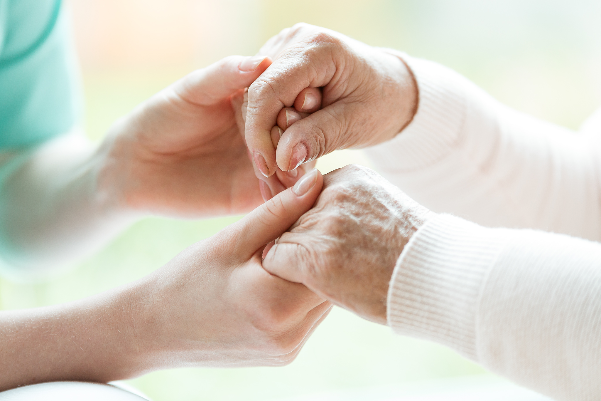 Photo with close-up of caregiver and patient holding hands