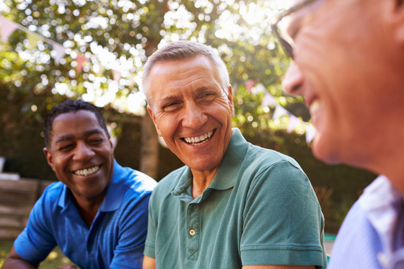 Mature Male Friends Socializing In Backyard Together