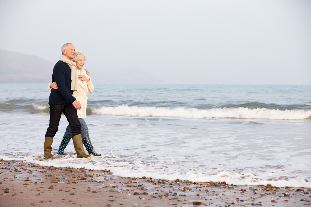 Senior Couple Walking Along Winter Beach Relaxing
