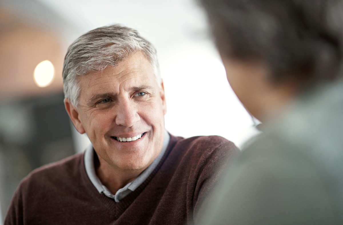 Shot of a mature man having a conversation with someone blurred out in the foreground