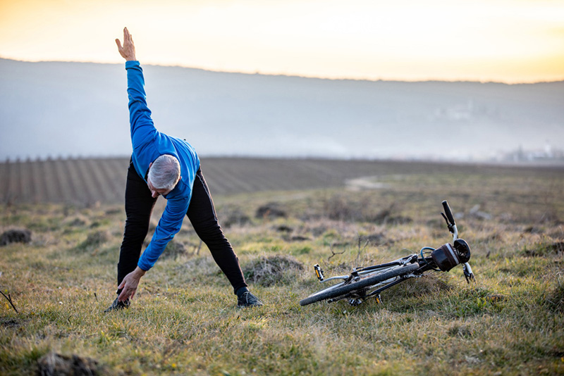 Active Senior Man Cyclist Stretching in Rural Scene.